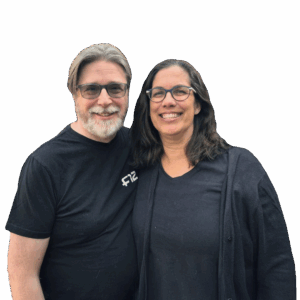 Mike & Chantal Davies smiling and standing side by side, both wearing glasses and dark tops