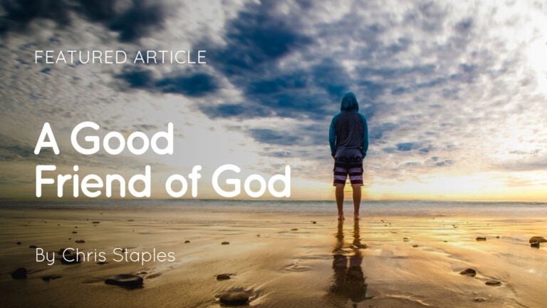 Person in a hoodie and shorts standing on a reflective wet beach looking out to a dramatic cloudy sunrise over the sea
