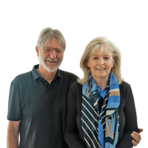Bill and Janet standing close and smiling; Bill in glasses and a dark polo, Janet wearing a blue patterned scarf