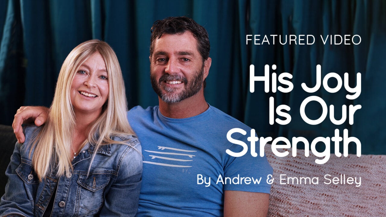 Andrew and Emma Selley sitting on a sofa smiling with video title text "His Joy Is Our Strength" visible