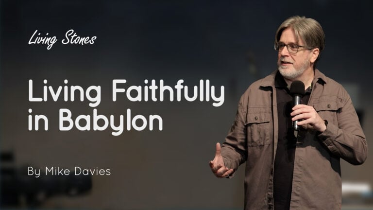 Speaker Mike Davies holding a microphone on stage for Living Stones 'Living Faithfully in Babylon'