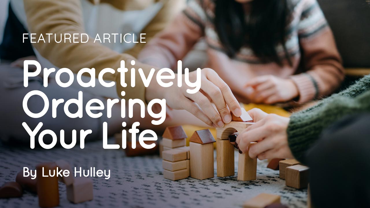 Hands of several people arranging wooden block houses on a table with overlaid title 'Proactively Ordering Your Life' by Luke