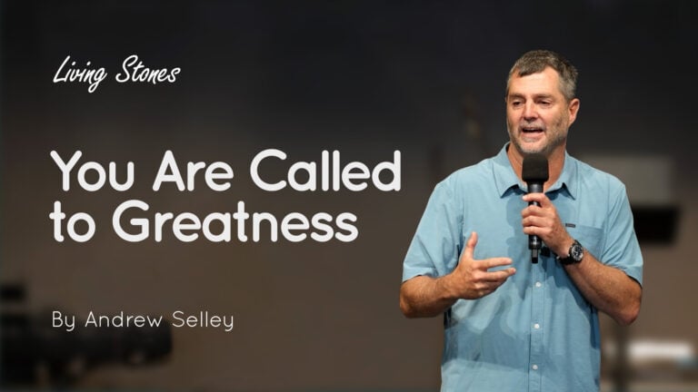 Andrew Selley speaking into a microphone on stage with the title 'You Are Called to Greatness' and 'Living Stones'
