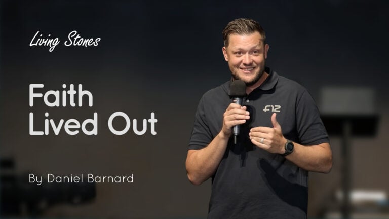 Speaker Daniel Barnard holding a microphone on stage with the text ‘Faith Lived Out’ beside him