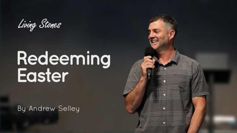 Man holding a microphone on stage beside a slide reading ‘Living Stones Redeeming Easter By Andrew Selley’