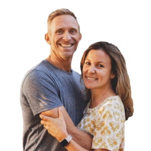 Brad Verreynne and Angela smiling and embracing, Brad in a grey t-shirt and Angela in a floral top