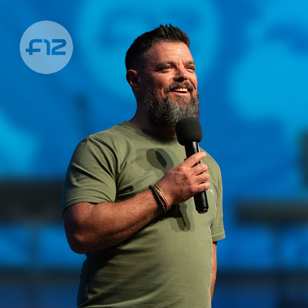 Man with beard holding a microphone and smiling on stage (KevinAldridge)