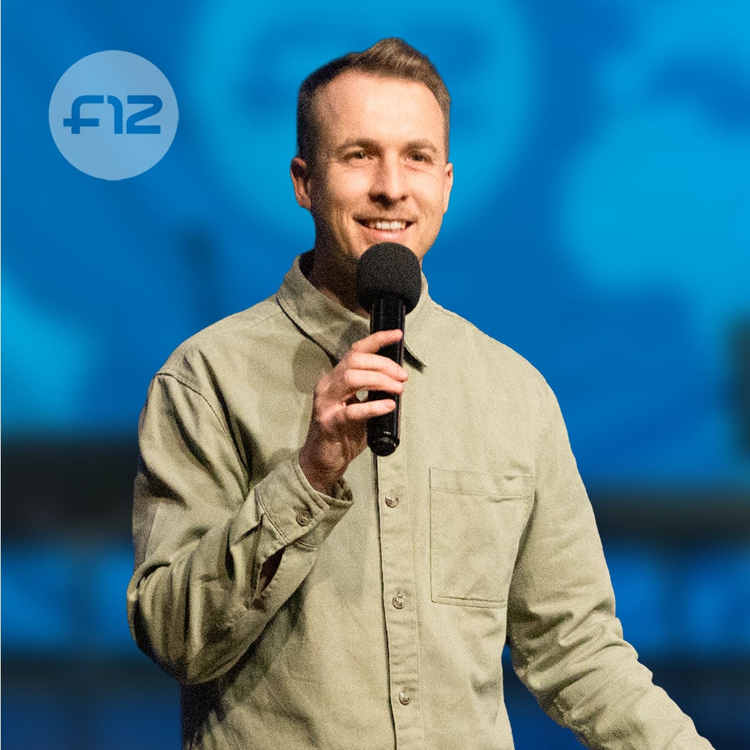 Smiling man holding a microphone mid-speech, identified as LeonardStrydom, against a soft blue background