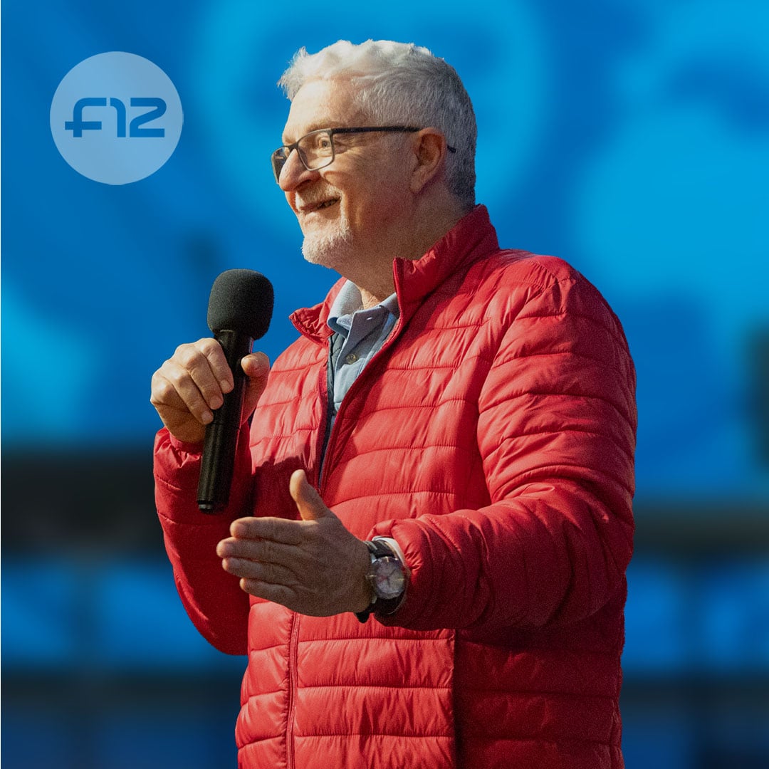 Russel Fraser, speaker wearing glasses and a red jacket, holding a microphone and gesturing