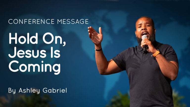 Speaker Ashley Gabriel on stage holding a microphone with projected title 'Hold On, Jesus Is Coming'