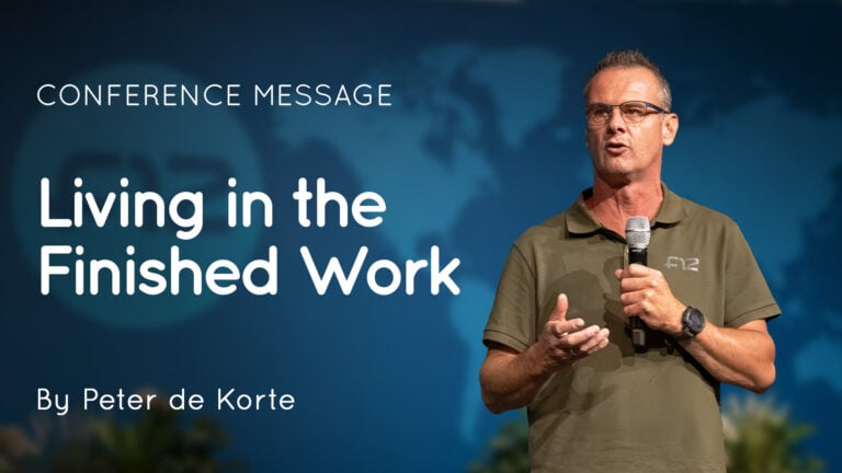 Male speaker holding a microphone on stage beside a slide reading "Living in the Finished Work" by Peter de Korte
