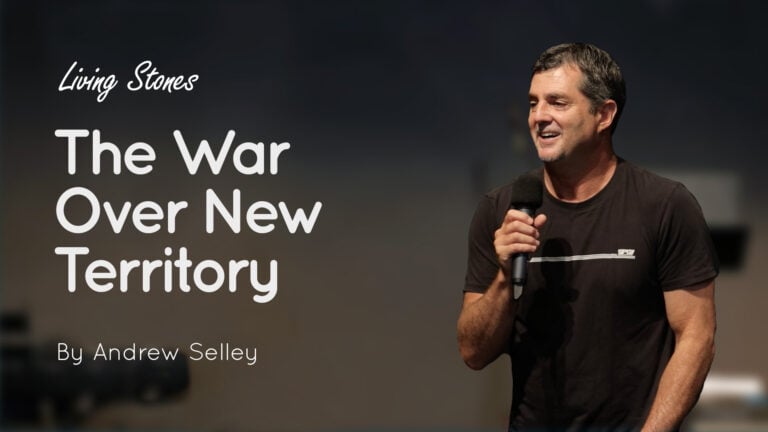 Man speaking into a microphone on stage beside the title text “The War Over New Territory” and “Living Stones”