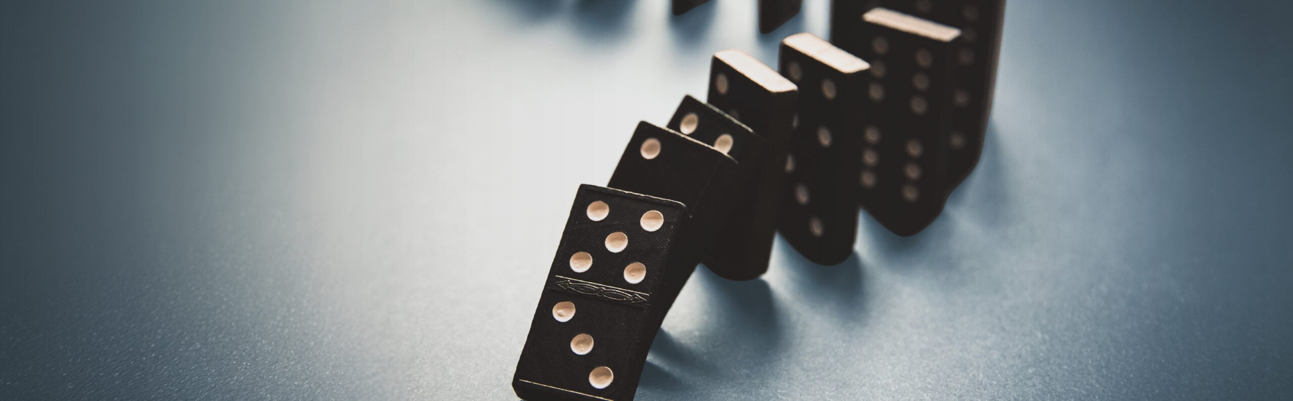 Close-up of a line of falling dominoes, with the nearest piece lying on its side