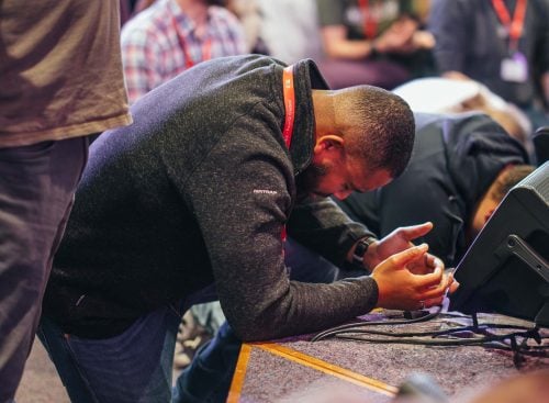 Man kneeling and praying at the front of a conference room during a School of Leadership event