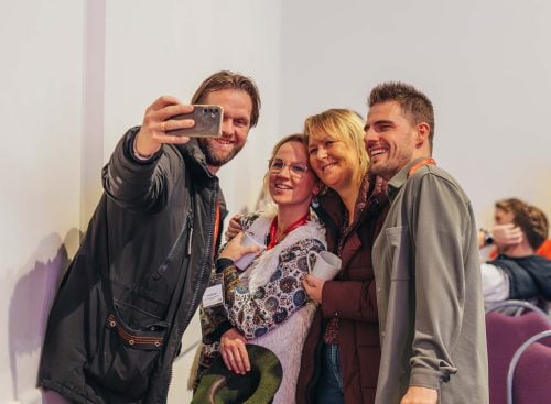 Four people smiling and taking a group selfie at the 2024 School of Leadership event