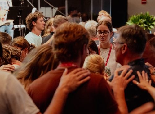Group of people praying and laying hands on one another at the 2025 conference in the USA